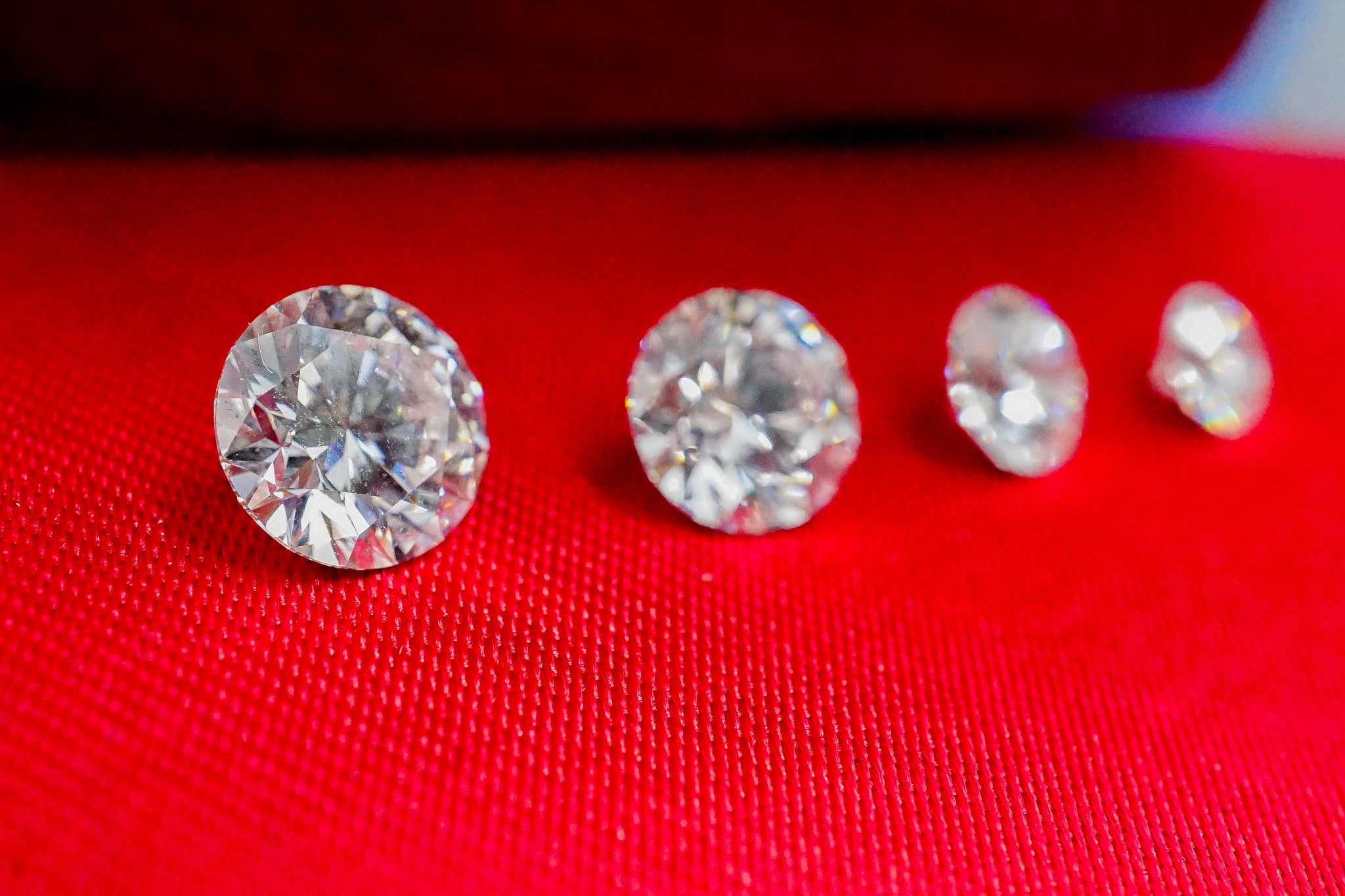 Four loose clear diamonds on a red fabric background (1.07 g).
