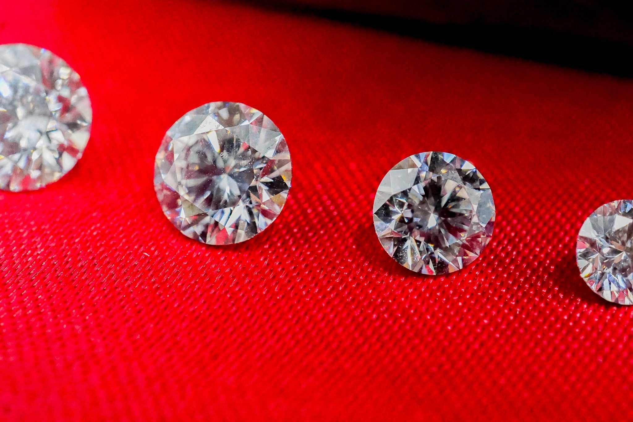 Four loose clear diamonds on a red fabric background