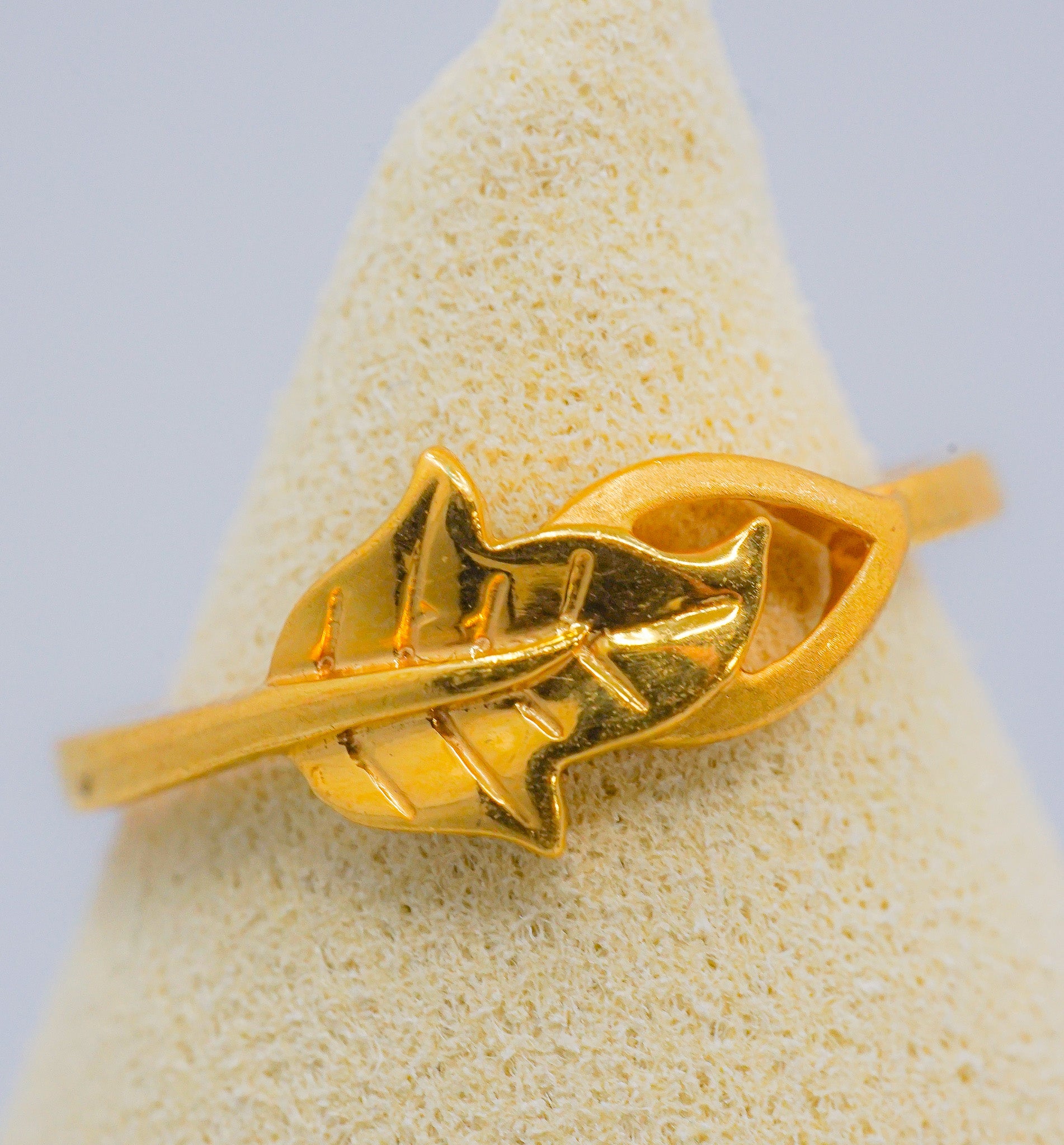 Front view of a 22K yellow gold leaf motif ring, size 6, on a display stand