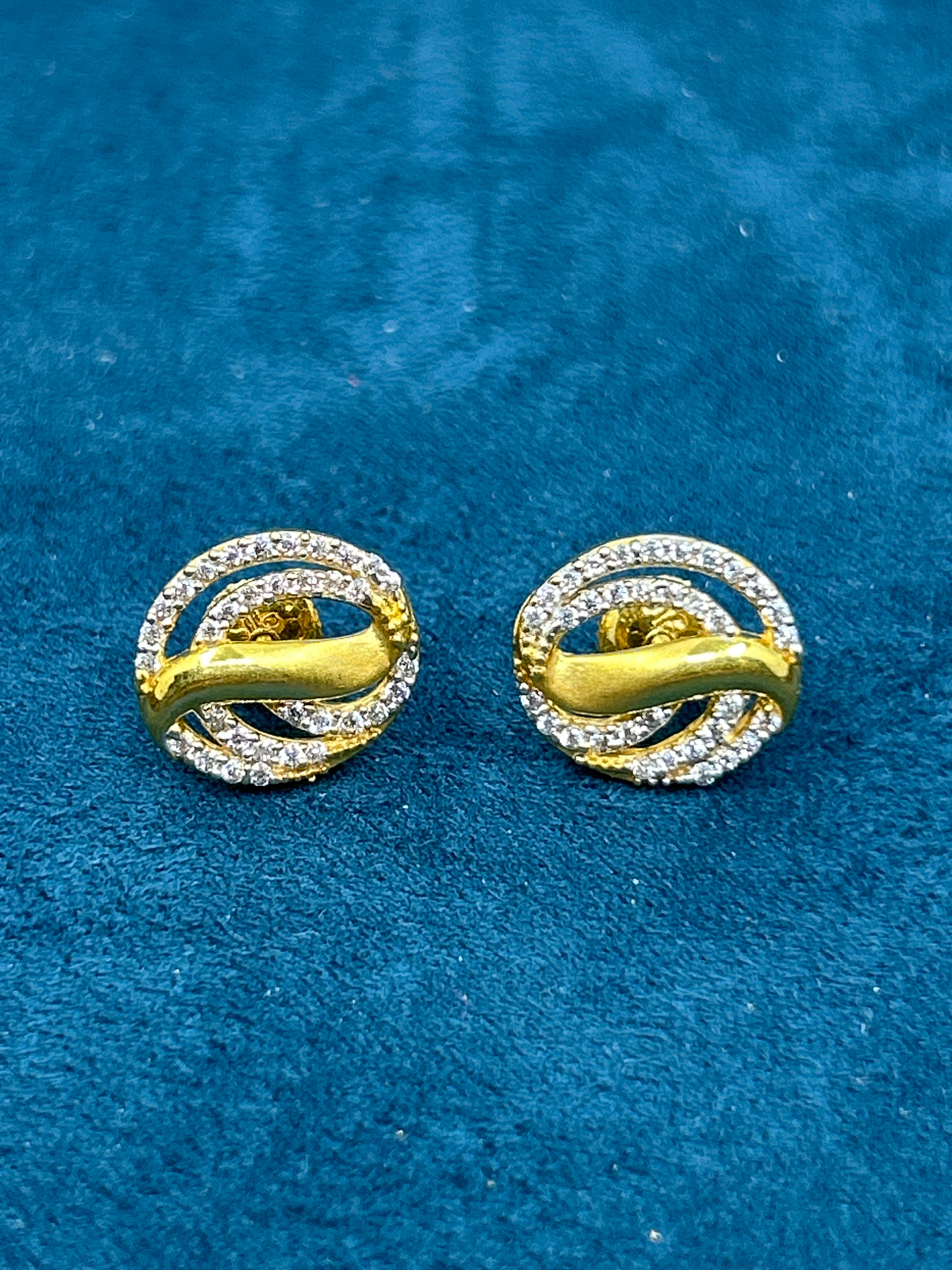 Gold and diamond earrings on a blue textured background