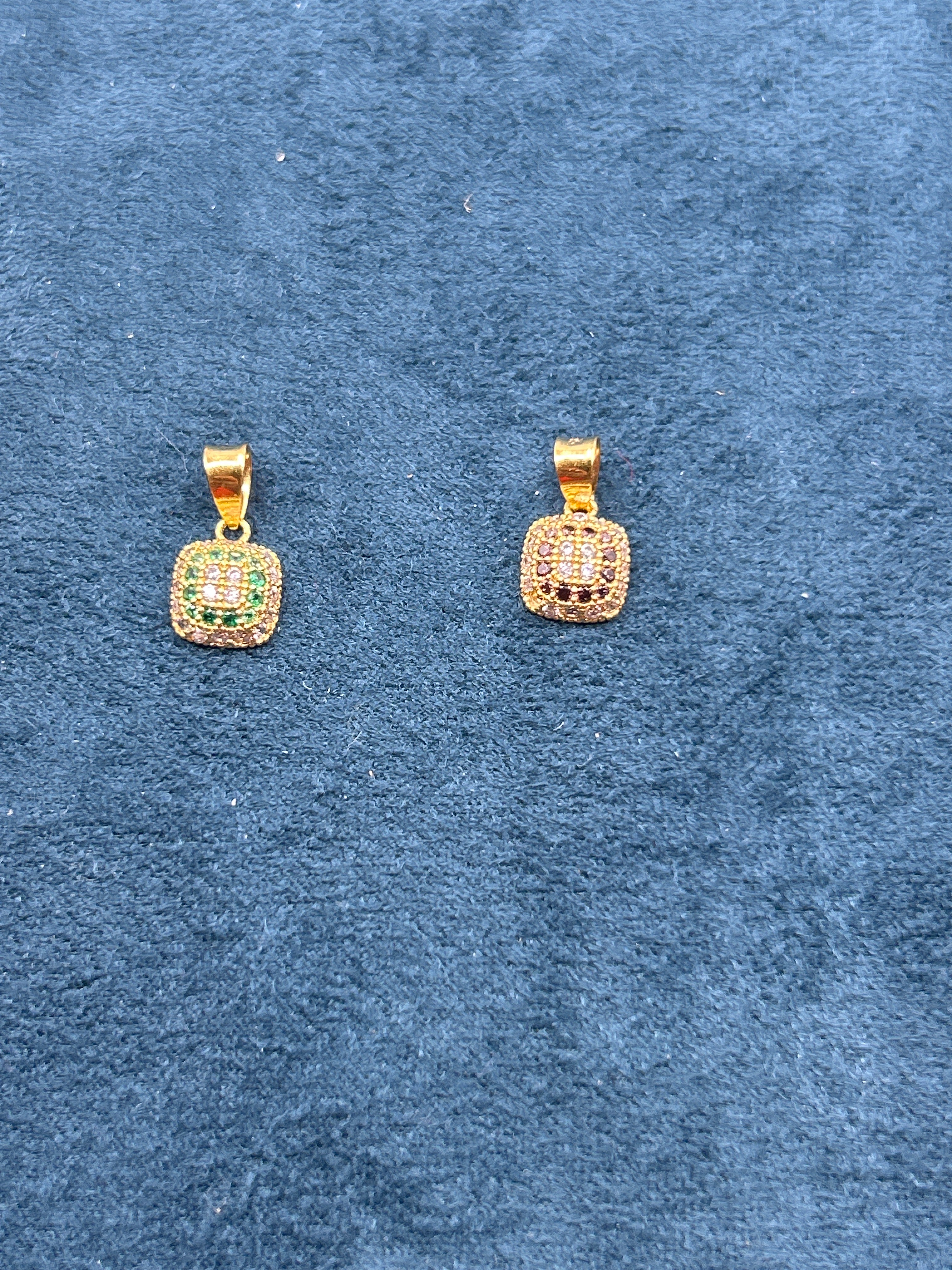 Gold earrings with gemstones on a blue textured background