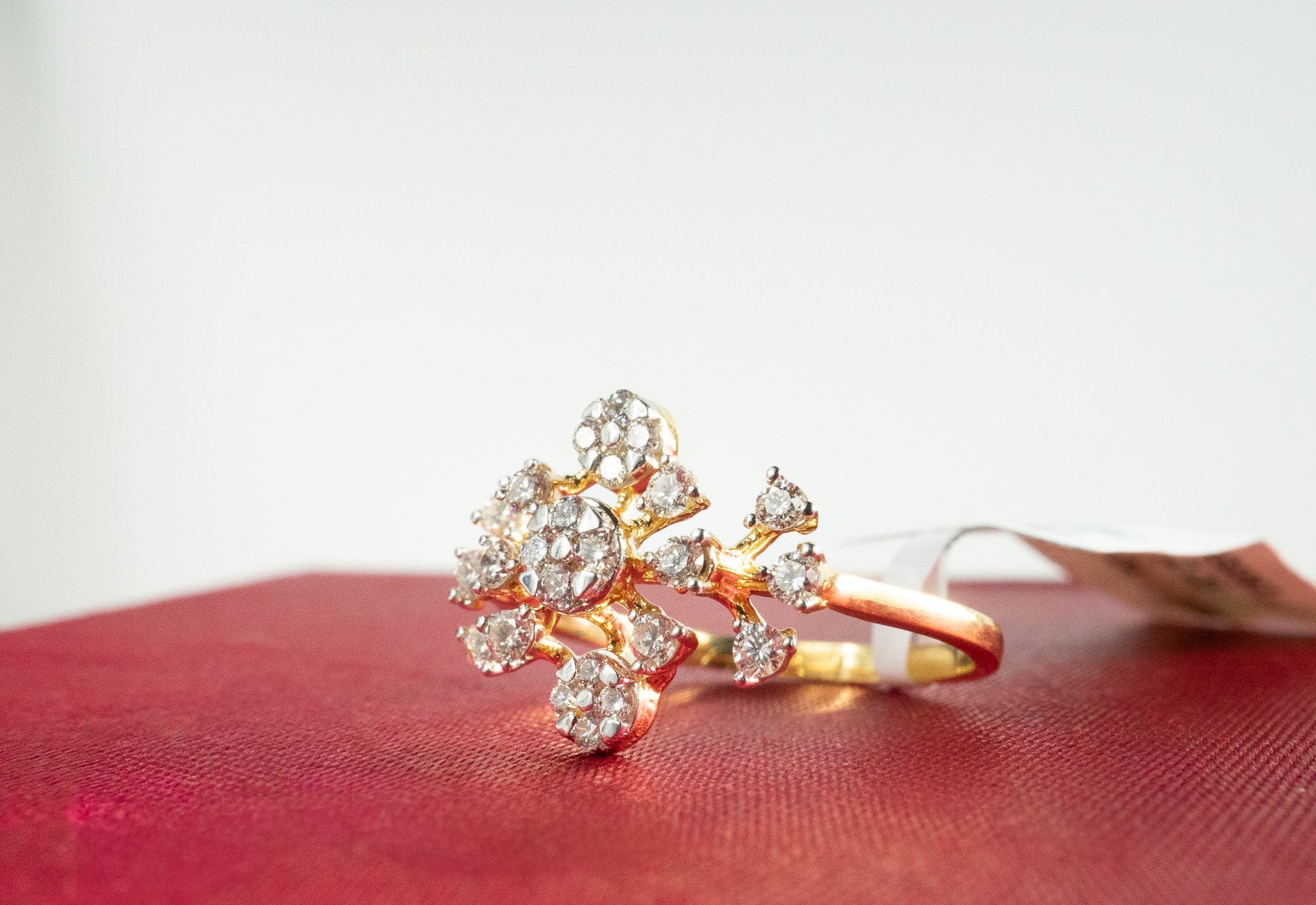  Gold floral cluster diamond ring with diamonds photographed on red background, side angle