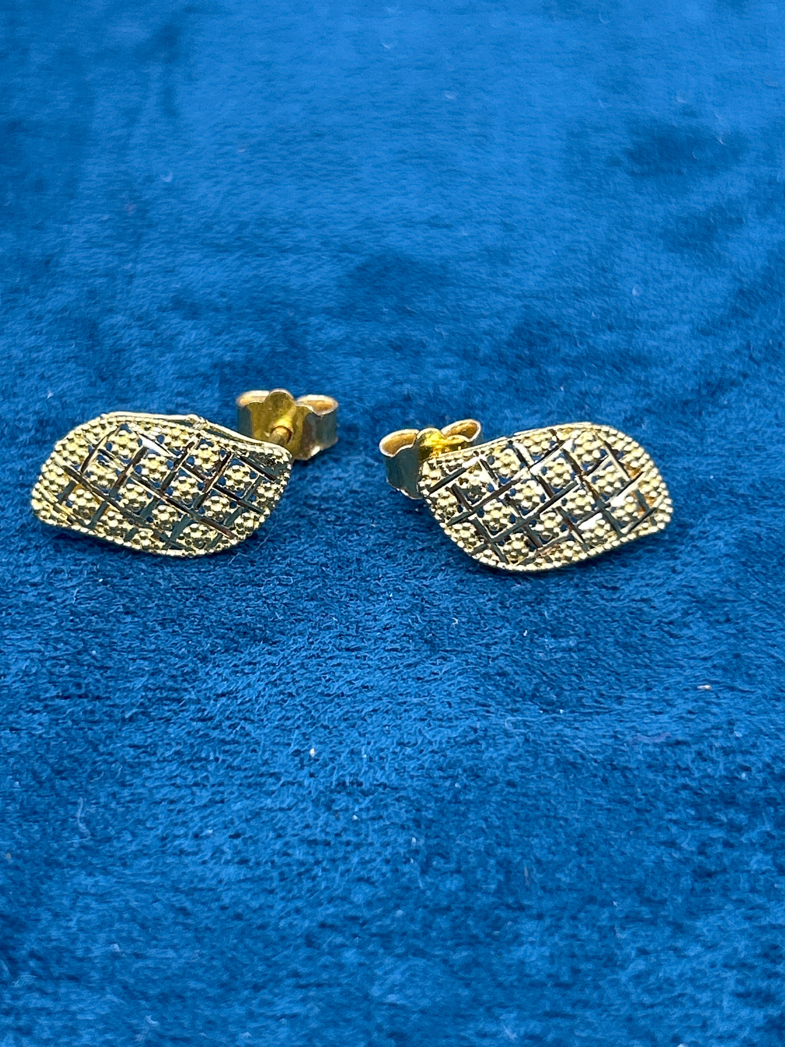 Gold leaf-shaped earrings on a blue textured background
