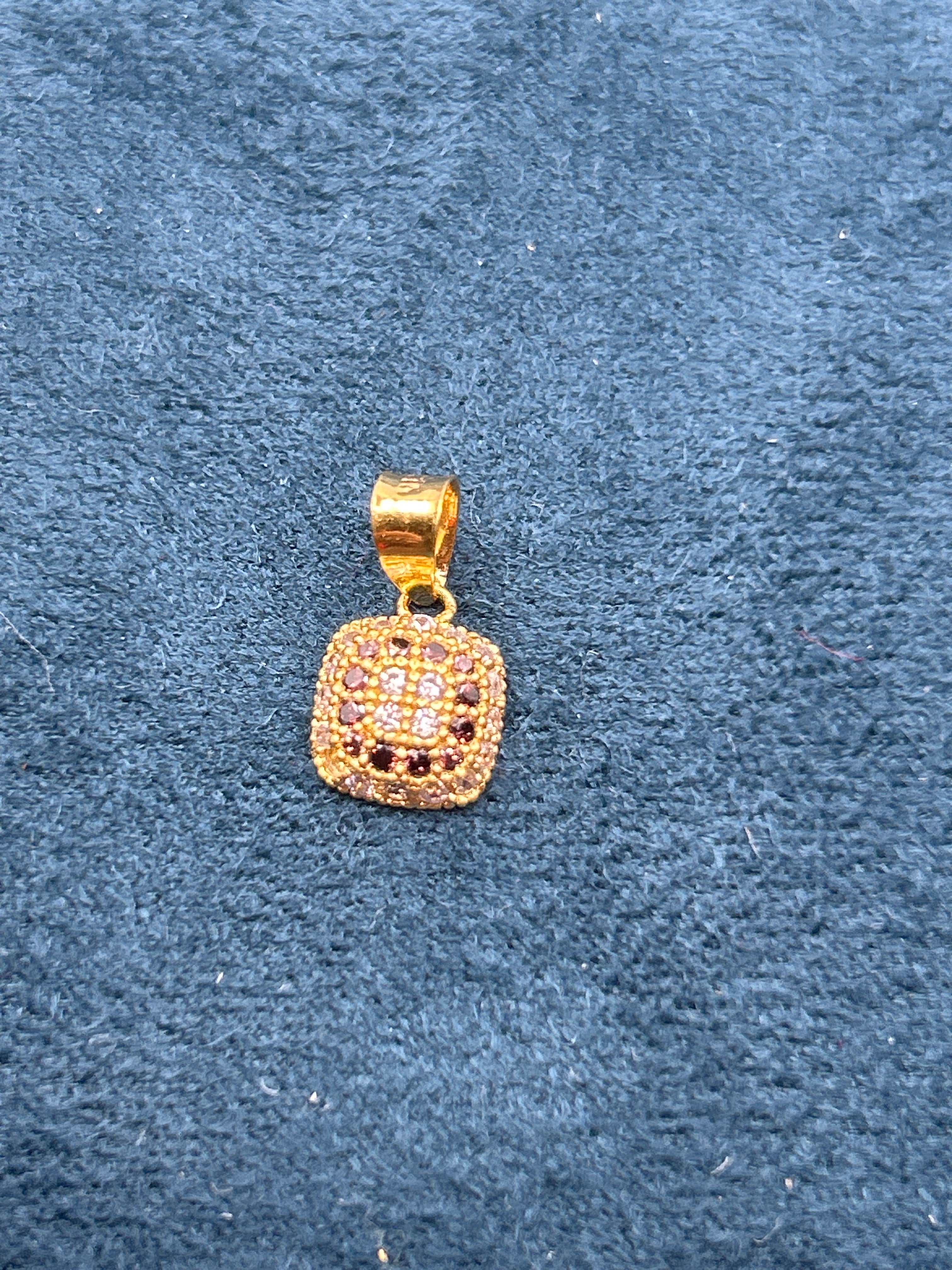 Gold pendant with black stones on a blue textured background