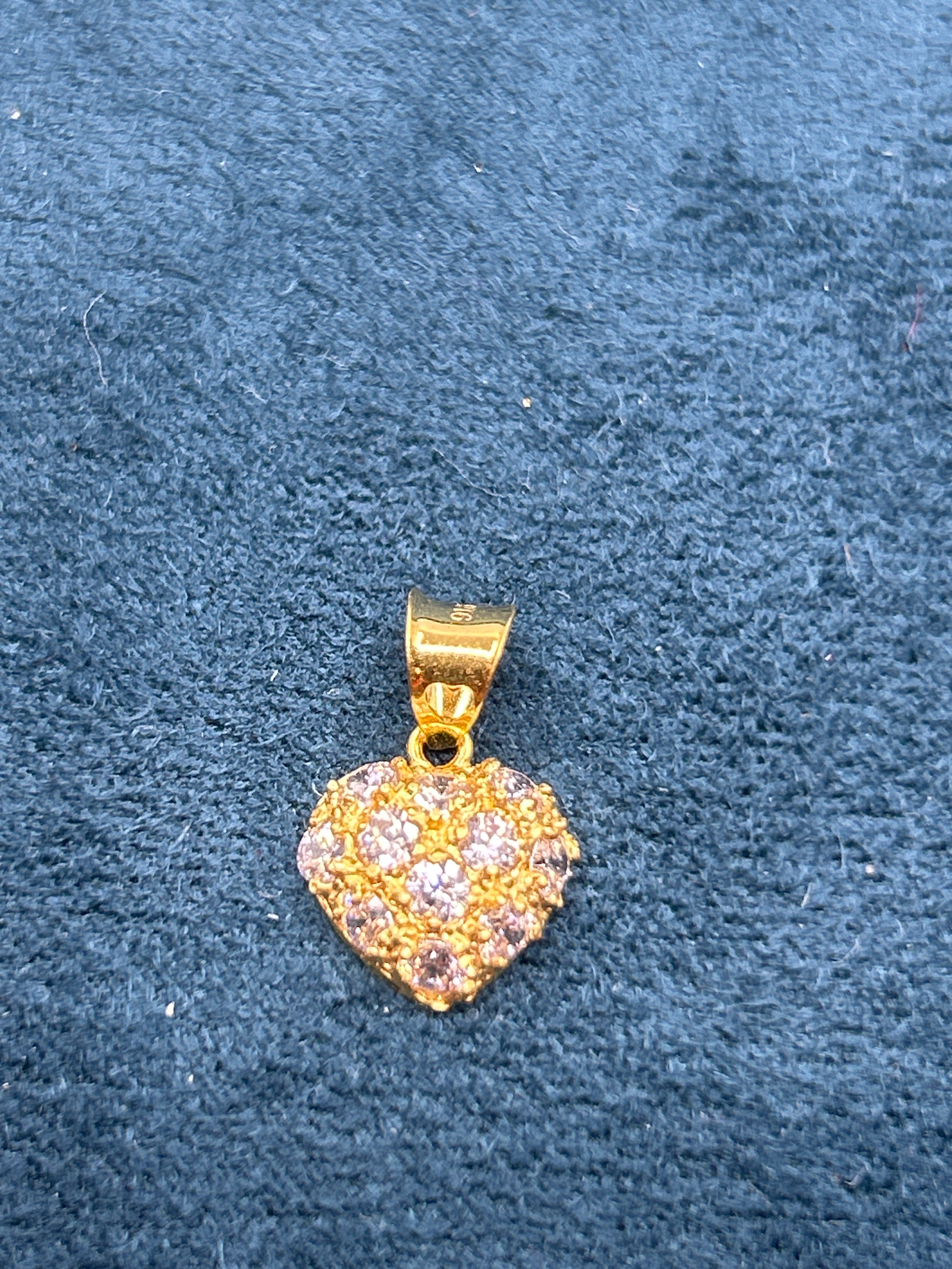 Gold pendant with gemstones on a blue textured background