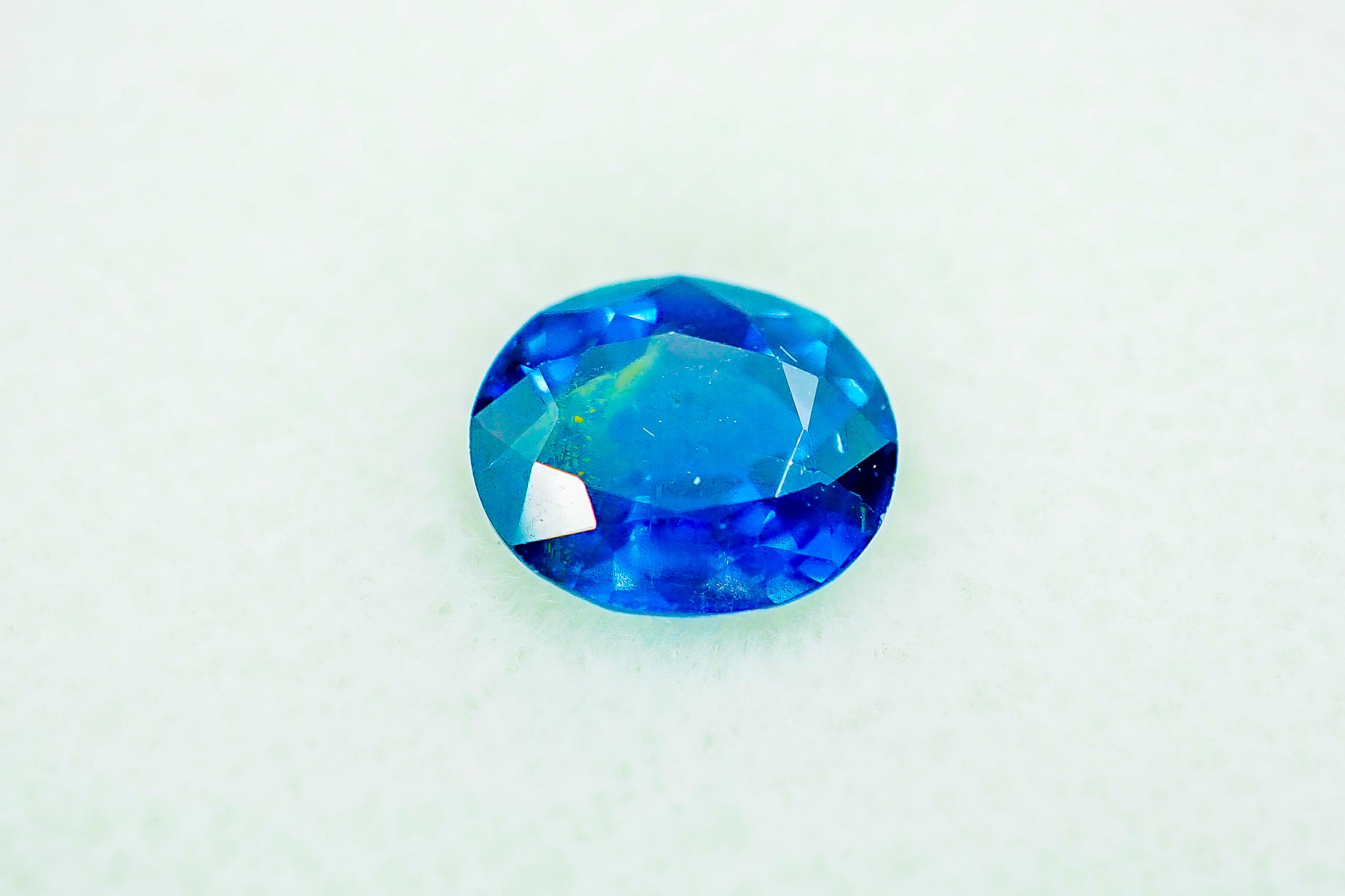 Loose oval blue sapphire gemstone (0.48 g) on a light background