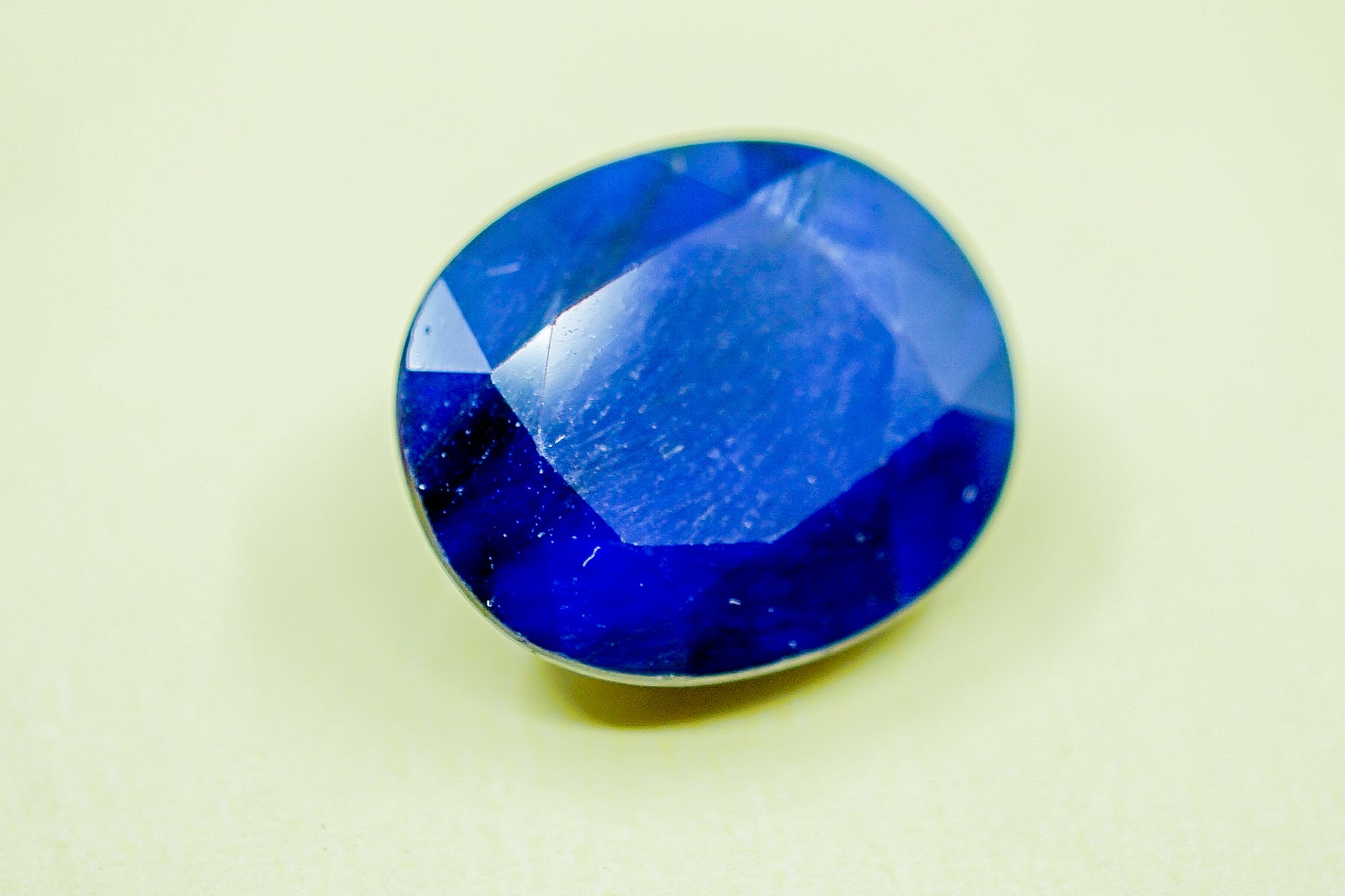  Oval faceted blue sapphire loose gemstone close-up on light green background, 2.53 g