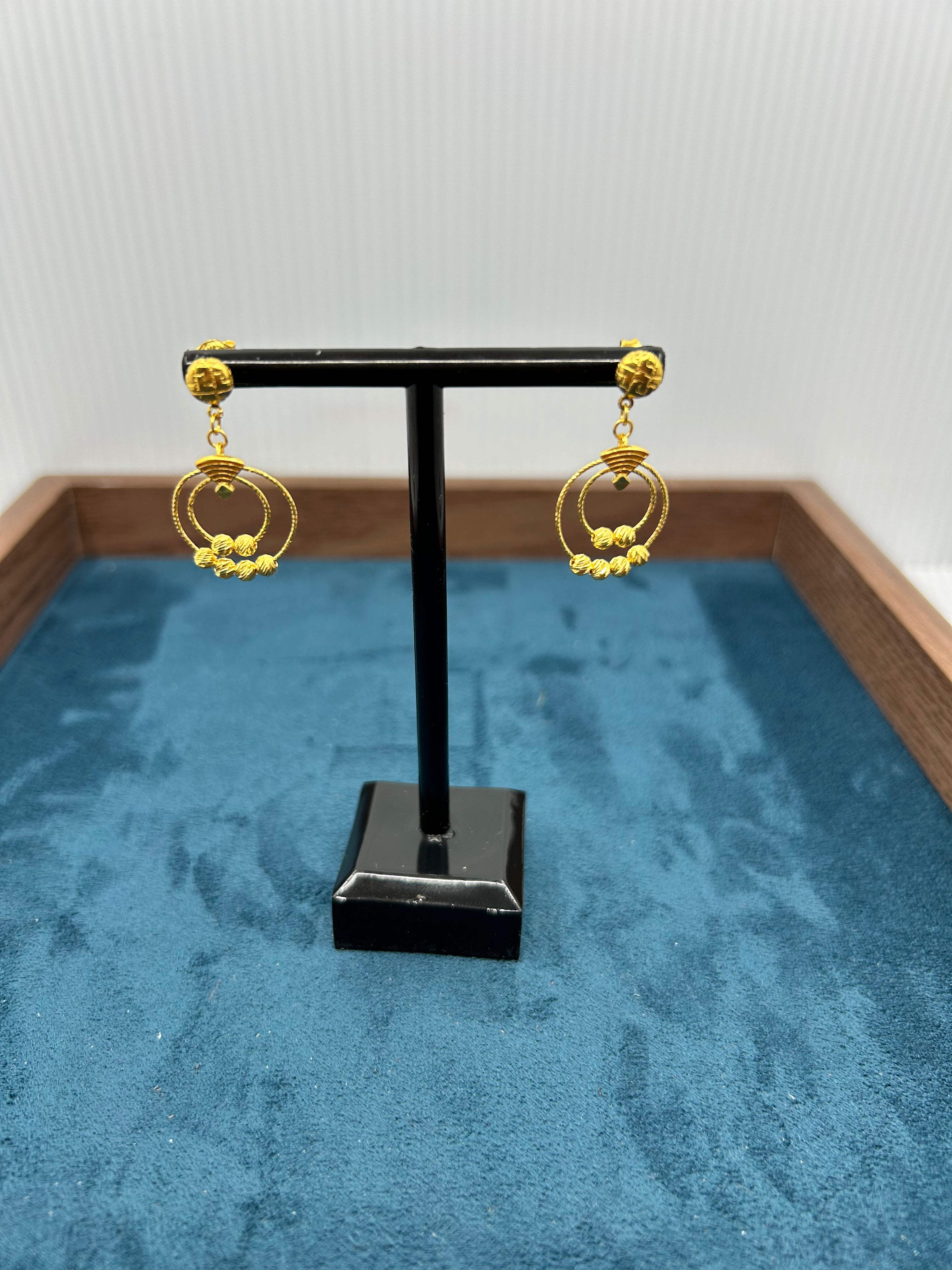 Pair of 22K gold dangle hoop earrings (4.21 g) on a black display stand