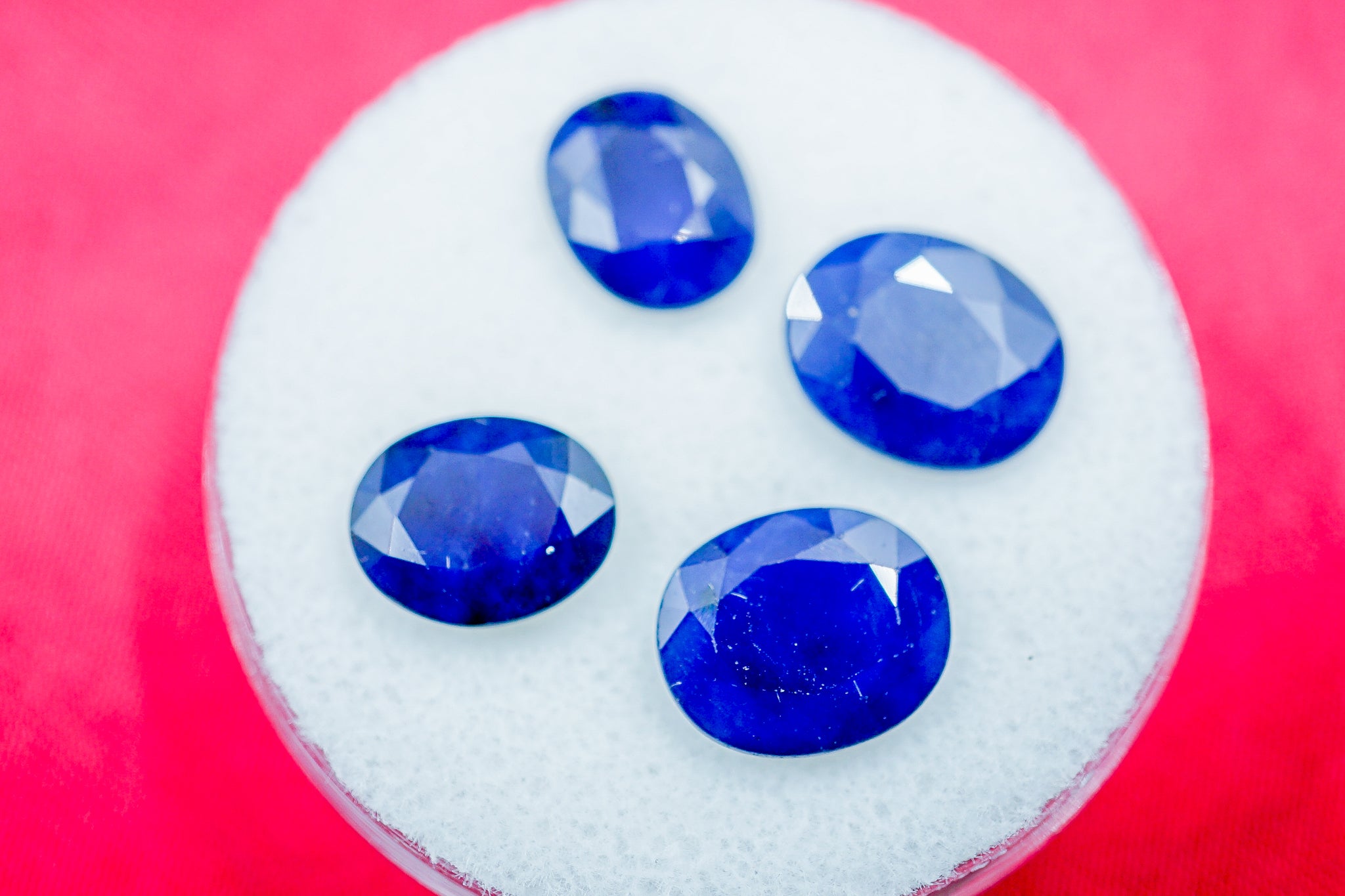 Set of four blue sapphire gemstones shown on a white round pad