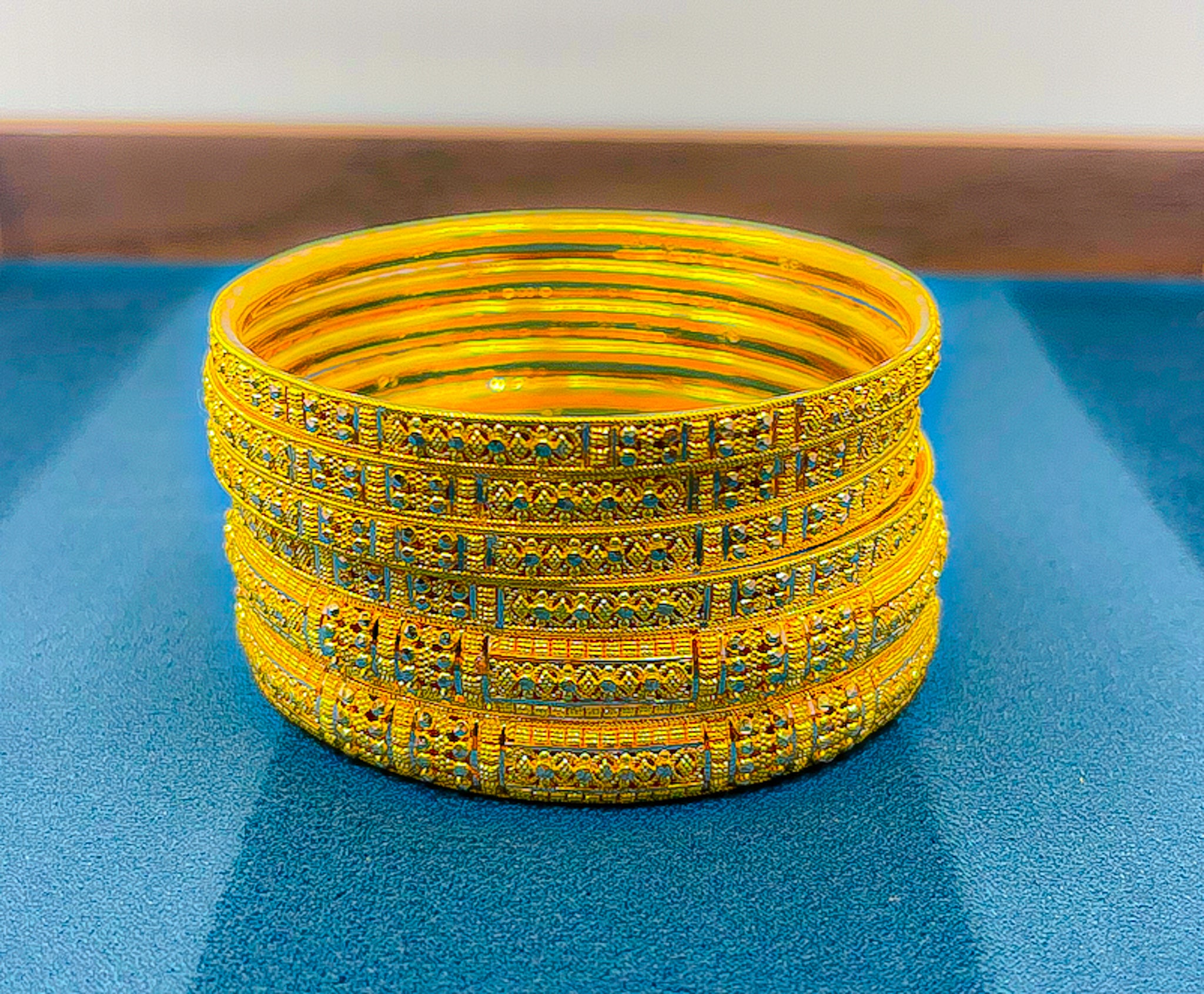 Six 22K yellow gold slim bangles arranged together showing matching engraved pattern