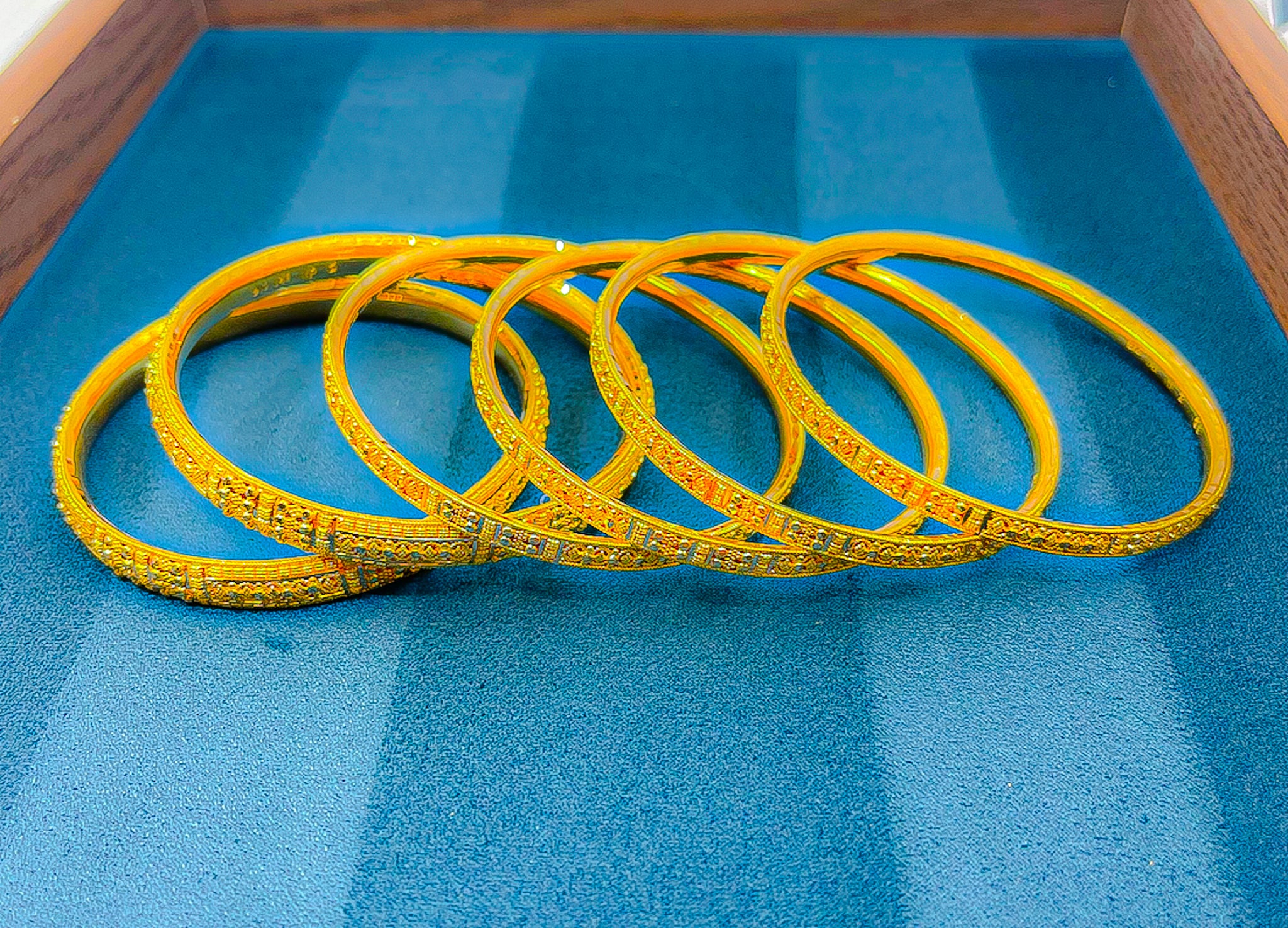 Six 22K yellow gold slim bangles arranged together showing matching engraved pattern