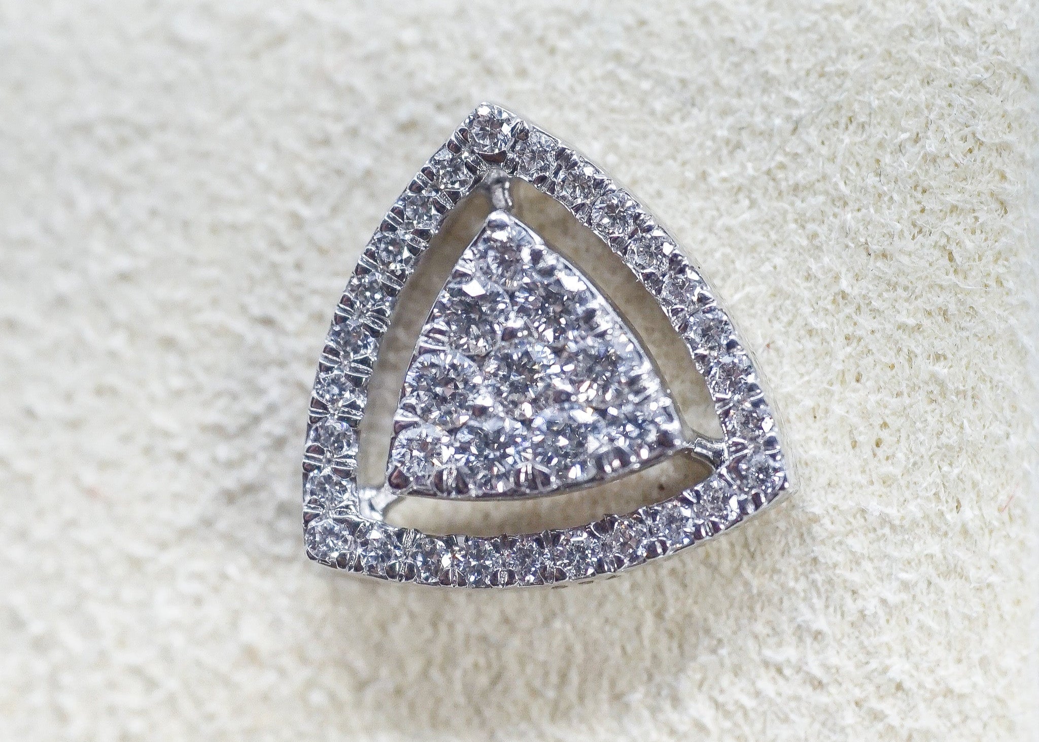 Velvet Spark triangle-shaped diamond earring in 18K gold with pavé-style diamonds on a textured background.