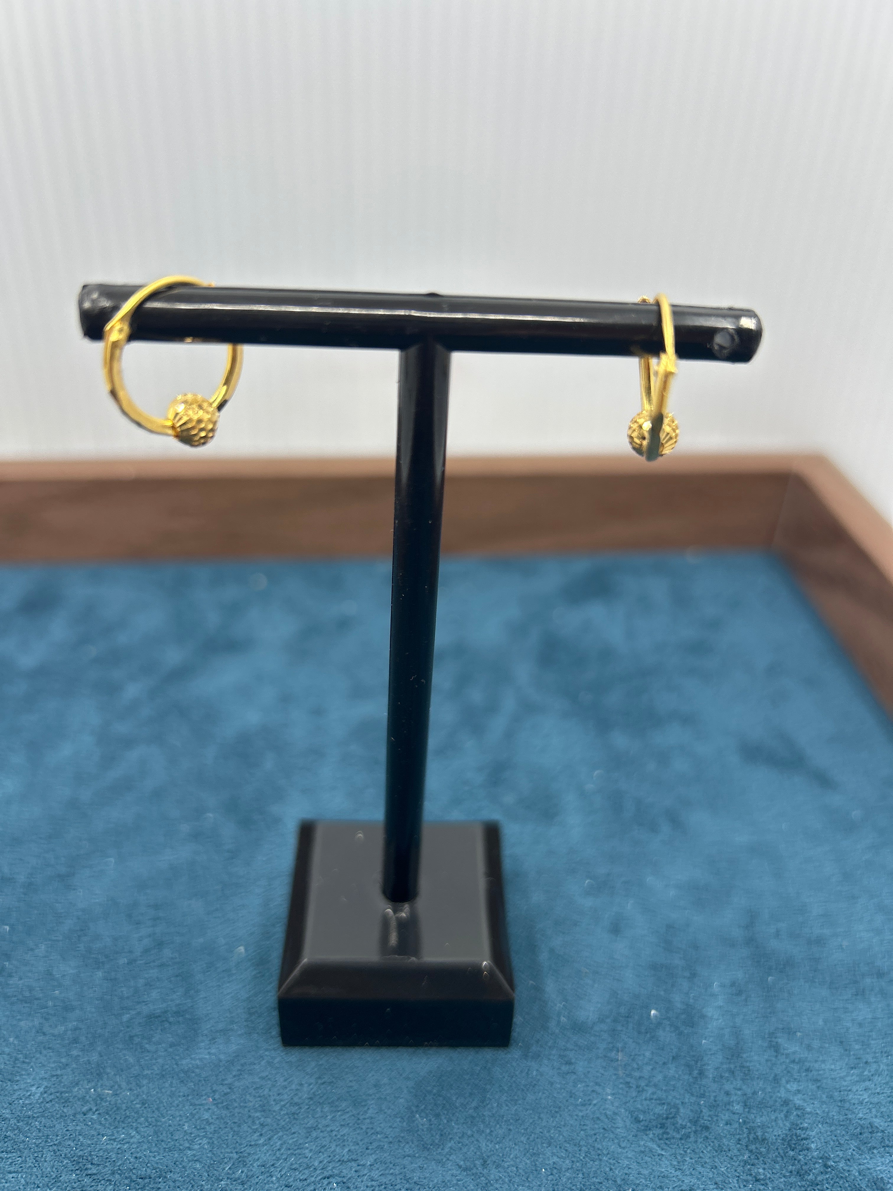 Black and gold jewelry stand against a blue textured background