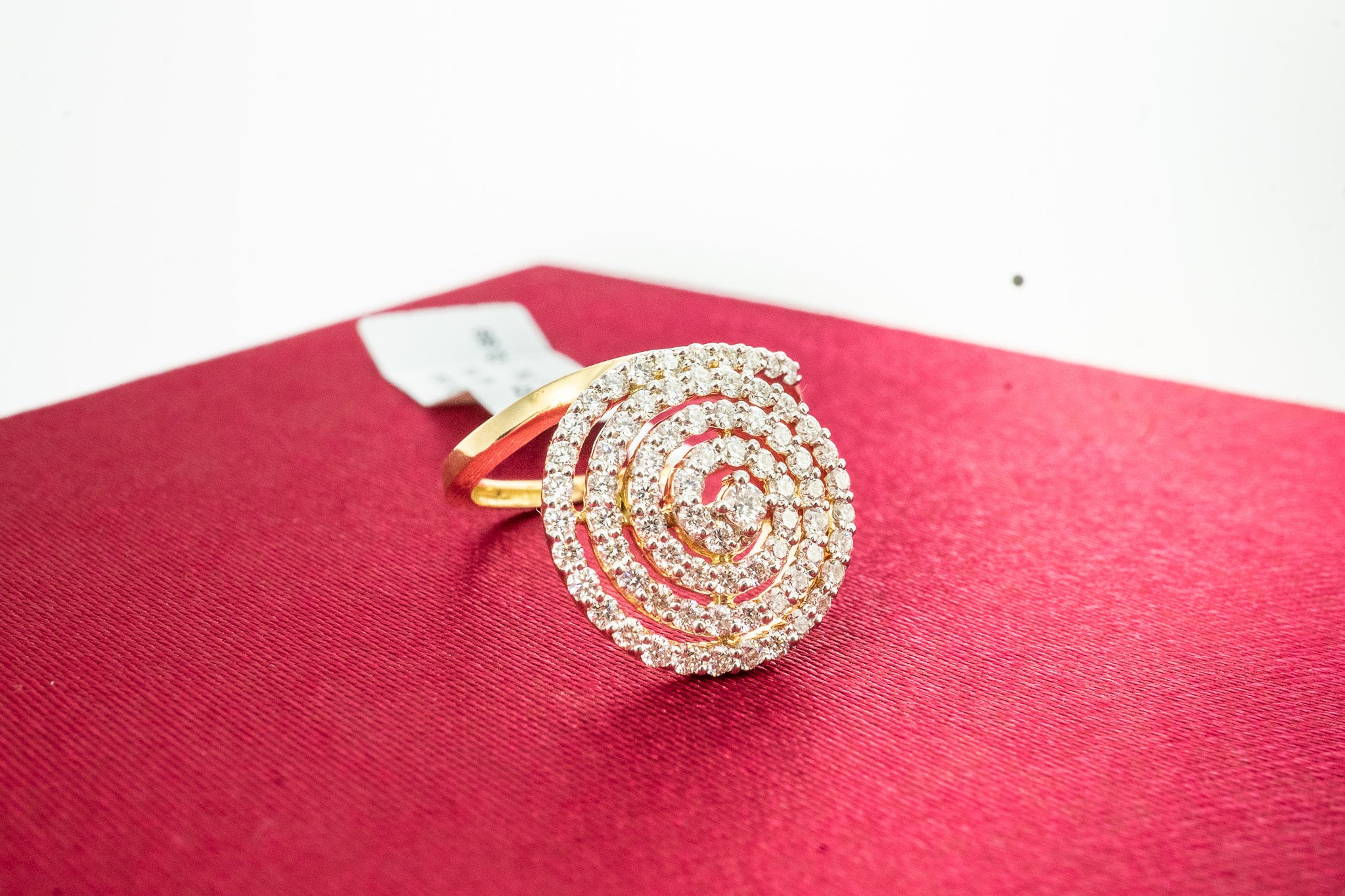 Moonflare 18K gold diamond ring with round spiral cluster face, 0.88 carat total diamond weight, on red fabric background.