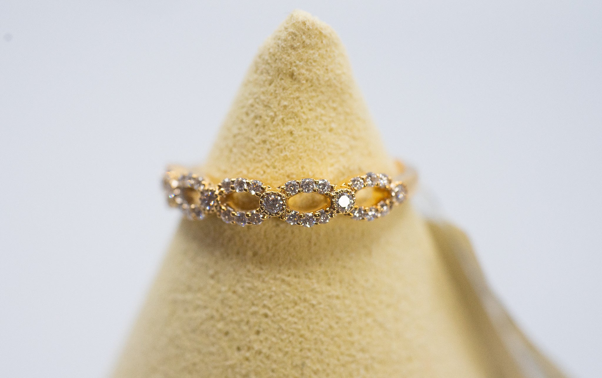 18k gold diamond oval link band ring (0.22 carat total diamond weight) shown on a ring stand